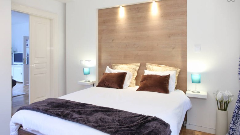 Zimmer, © 2015 Modernes Schlafzimmer mit Doppelbett, Holzrückwand und blauen Nachttischlampen.