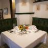Einkehren und urlauben in Baden, © Martinek: Feelimage/Matern Gemütliche Restaurant-Ecke mit grünem Kachelofen, gedecktem Tisch und Blumen.