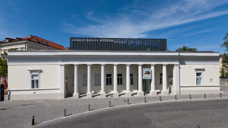 Arnulf Rainer Museum, © Kollektiv Fischka Exterior view of the Arnulf Rainer Museum with columned façade and blue sky.