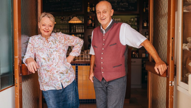 A man and a woman stand smiling in the doorway of a pub.