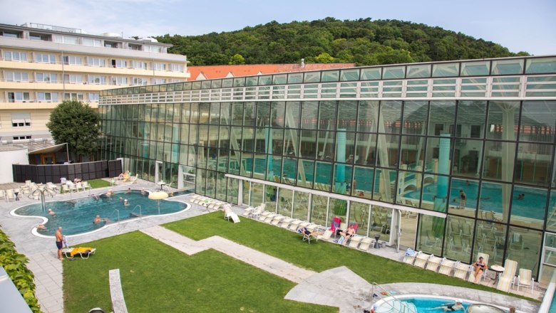 Exterior view of the R&ouml;mertherme Baden with pool and glass fa&ccedil;ade.