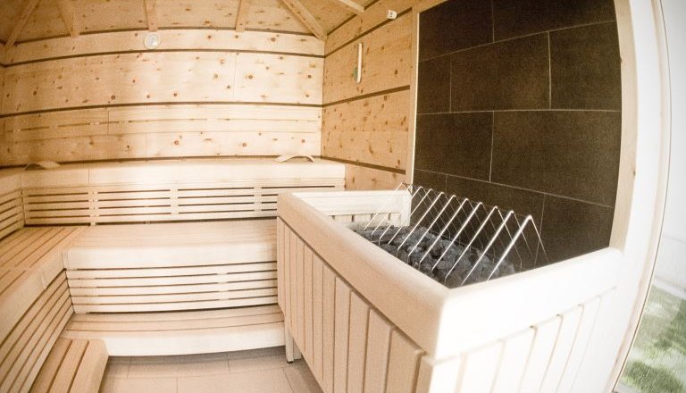 Interior view of a modern sauna with wooden benches and stove.