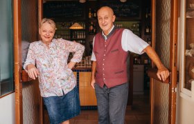A man and a woman stand smiling in the doorway of a pub.