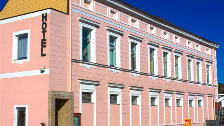 Haus, © Hotel Artner Ein rosa Gebäude mit der Aufschrift 'Hotel' an der Fassade.