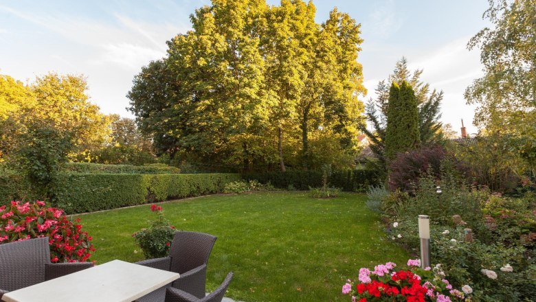 A well-kept garden with lawn, flower beds and garden furniture on a terrace.