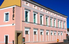 A pink building with the word 'Hotel' on the fa&ccedil;ade.