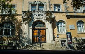 Eingang des Rollettmuseums mit verziertem Torbogen und Treppe.